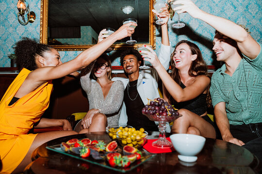 Diverse friends enjoying cocktails and toasting during a social party