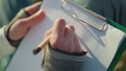 writing in nature, hands recording data outdoors under sunlight, recording observations during survey in natural environment, taking notes outdoors while conducting field study on sunny day