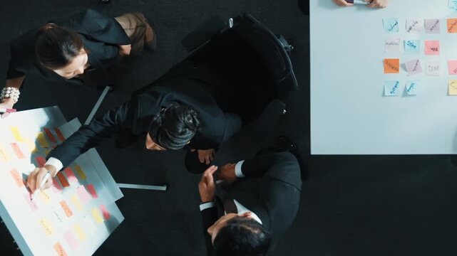 Top view of smart business group write marketing idea at whiteboard while present to executive manager. Investor clapping hands to celebrate successful project at table with sticky notes. Directorate.