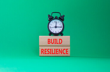Build resilience symbol. Wooden blocks with words Build resilience. Beautiful green background with alarm clock. Business and Build resilience concept. Copy space.