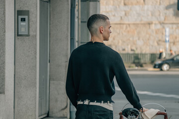 young man walking on the street with bicycle on his back