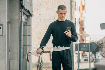 young man walking on the street with phone and bicycle