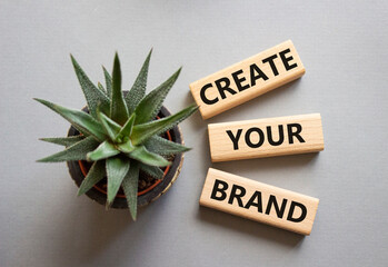 Brand symbol. Concept words Create your Brand on wooden blocks. Businessman hand. Beautiful grey background with succulent. Business and Create your Brand concept. Copy space.