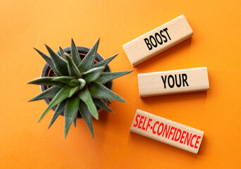 Self-confidence symbol. Concept word Boost your Self-confidence on wooden blocks with succulent. Beautiful orange background. Business lifestyle and Self-confidence concept. Copy space
