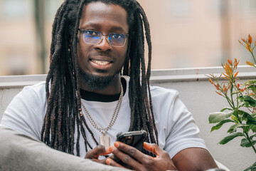 young african man with dreadlocks and mobile phone on the terrace