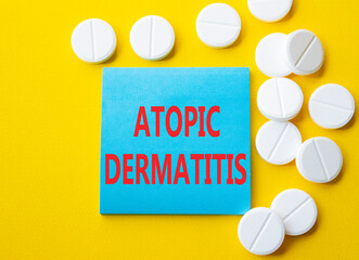 Atopic Dermatitis symbol. Concept word Atopic Dermatitis on blue note. Beautiful yellow background with pills. Medicine and Atopic Dermatitis concept. Copy space
