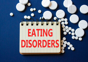 Eating Disorders symbol. Concept word Eating Disorders on notebook. Beautiful deep blue background with pills. Medicine and Eating Disorders concept. Copy space