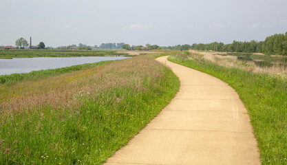 Cycle path runs along sea dike near Putter steam pumping station in Netherlands on sunny day