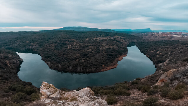 Breathtaking natural landscape of the Duero River forming a spectacular horseshoe bend, seen from the rocky cliffs of the viewpoint in the province of Soria, Castilla y Le&oacute;n, on an overcast day.