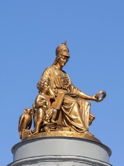 Fototapeta premium Saint Petersburg, Russia - May 01, 2025. Gilded rooftop statue on the Imperial Academy of Arts building on Universitetskaya Embankment against a clear blue sky