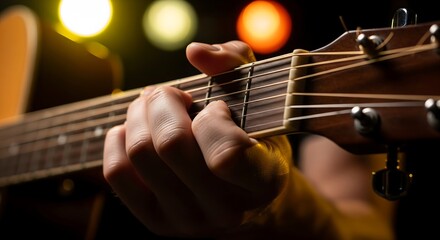 Fototapeta premium Close-up of musician's hand playing acoustic guitar strings with colorful bokeh lights background, focus on fingers on fretboard.