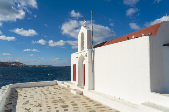 View of a brilliant white church stands against the deep blue sea and sky, a striking contrast of color and form, Old town, Mykonos, Greece.