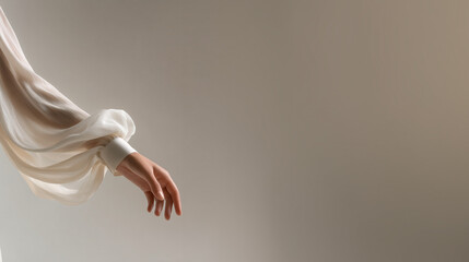 Graceful female hand in sheer white blouse sleeve against neutral background with copy space