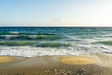 View of the tranquil turquoise waves gently kissing the golden sand under a serene blue sky, inviting peaceful contemplation, Mykonos, Mykonos, Greece.