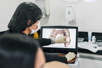 Dentist reviewing digital dental images on a computer screen with a female patient during a...