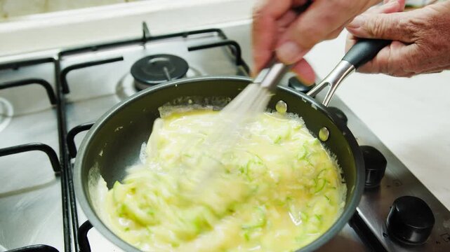 Cooking an omelette with eggs and courgettes in typical Sicilian cuisine