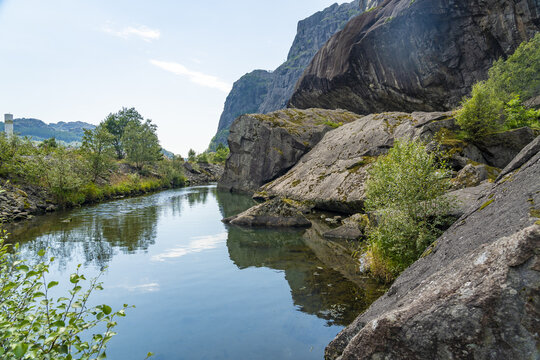 View of calm waters reflect the sky amidst rugged rock formations and vibrant green vegetation, a serene natural landscape, Helleren, Jossingfjord, Norway.