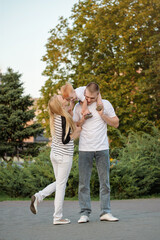 Happy family is playing cheerfully outdoor in the summer. Dad, mom and son are hugging together