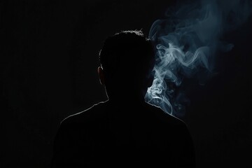 Silhouette of a person with smoke, against a black background shows mystery