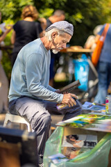 22.09.2023 Pezinok Slovakia Street artist painting beautiful pictures of the Spey landscape at the fair. A dangerous profession for health