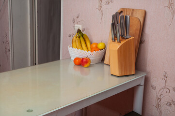 Kitchen counter with fresh fruit in a basket and a knife block with sharp knives