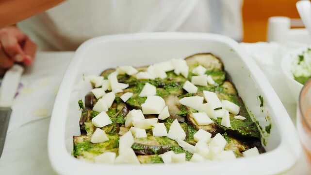 A womans hands preparing an eggplant and provola lasagna