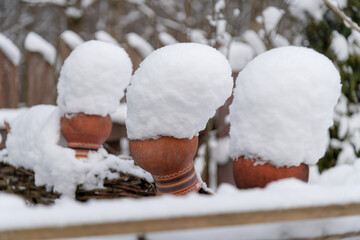 Snow covers clay pots in a garden during winter season
