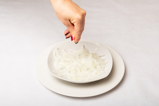 salando ensalada de cebolla picada en pluma con la mano