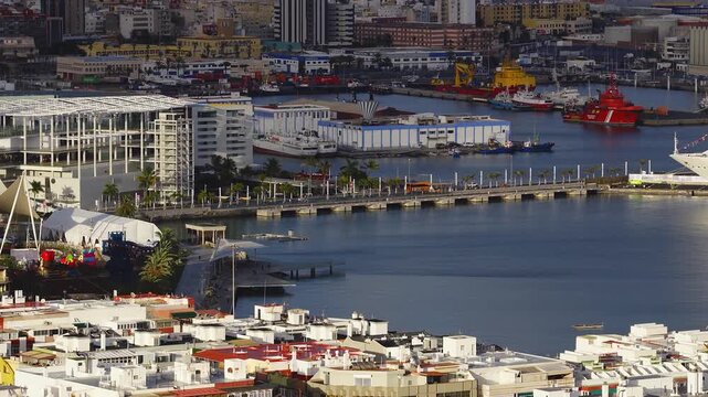 Aerial late afternoon view of Las Palmas harbor, Muelle de Santa Catalina, Costa cruise liner, el muelle sign, palm promenade, cranes, boats, and calm water reflections.
