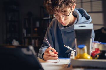 Teenager student painting with brush, focus on learning homework art creativity indoors