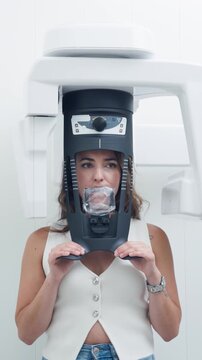 Young woman's face during a panoramic dental x-ray. Advanced tomography equipment scanning the patient's jaw in a modern dental clinic. Vertical footage