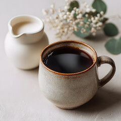 Cozy cup of black coffee and milk pitcher with white flowers on neutral background