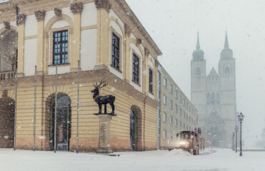 Historic Altermarkt square Magdeburg at heavy snowfall show Rathaus architecture, statues lanterns empty urban space winter storm. Municipal service tractor cleaning snow with snow plow
