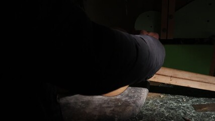 Professional luthier working on an acoustic guitar body. Close-up of male hands sanding and polishing the wooden surface in a dimly lit workshop during the manufacturing process.

