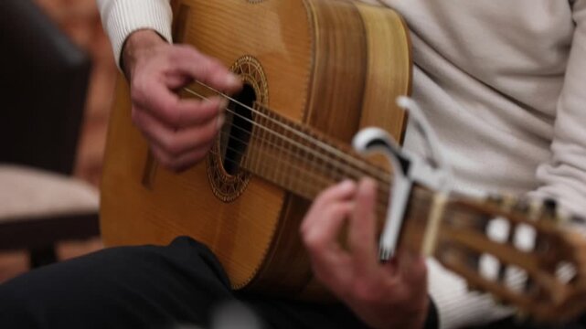 Close-up of musician tuning acoustic guitar using a mobile app on a smartphone screen, ensuring perfect pitch before playing a song during a music lesson.

