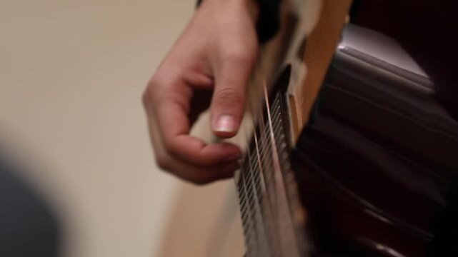 Close-up of musician tuning acoustic guitar using a mobile app on a smartphone screen, ensuring perfect pitch before playing a song during a music lesson.

