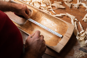 The master measures the distance on the tagelharpa billet with a ruler