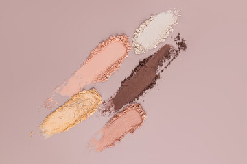 A set of several eyeshadow strokes in beige tones. Beautiful samples of the texture of dry eyeshadows of decorative cosmetics on a beige background.