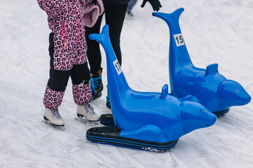 Photo of family, mother and daughter, woman and child skating on rink with helper seal for support.
