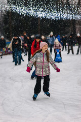 A beautiful happy smiling teenage girl or child skates on an outdoor rink in winter. Photography, portrait, sports, and leisure concept.