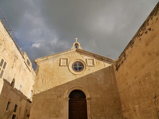 Fototapeta premium A low-angle vertical shot of the ornate limestone facade of St. Nicholas' Chapel in the historic 