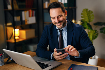 Smiling Businessman Using Smartphone At Desk