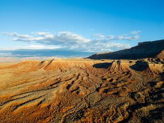 An aerial drone view captures the striking red rock mesas and deep, winding canyons near Hurricane, Utah, showcasing the rugged geological patterns of Gooseberry Mesa and the distant sandstone peaks o
