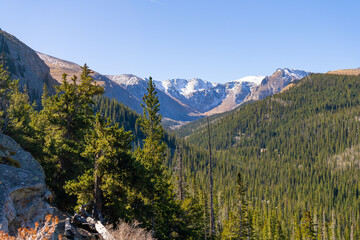 Hikers explore the alpine tundra of Mount Blue Sky (formerly Mount Evans) in Colorado. The trail offers expansive views of the Front Range and rugged peaks under a vast, bright blue sky.