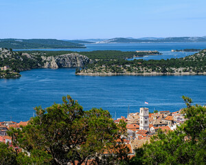 Obraz premium A high-angle view overlooking the red roofs of Šibenik town, the blue bay, and the many islands of the Dalmatian coast