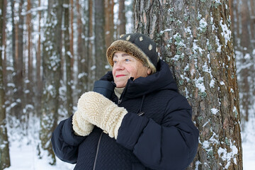 Portrait of a happy elderly woman holding a cup of coffee in the winter park.