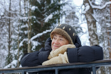 A smiling elderly woman in a winter public park. Winter outdoor recreation for the elderly.