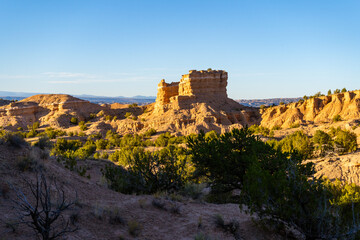 The Nambe Badlands glow under a warm golden hour light in New Mexico. Eroded sandstone formations...