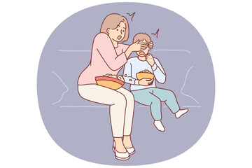 Shocked mother closes son eyes while watching television show with scenes of violence