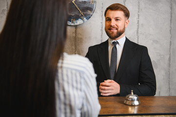 Hotel receptionist welcoming guest at reception desk